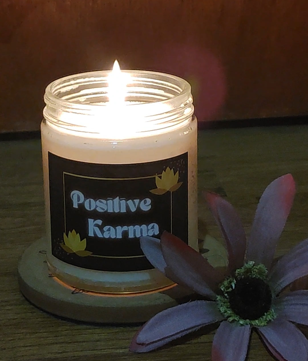 Scented candle illuminating home living space. Natural candle comes in 8 aroma options and many candle design choices. This spiritual candle depicts a mindful Positive Karma design with gold lotus accents.