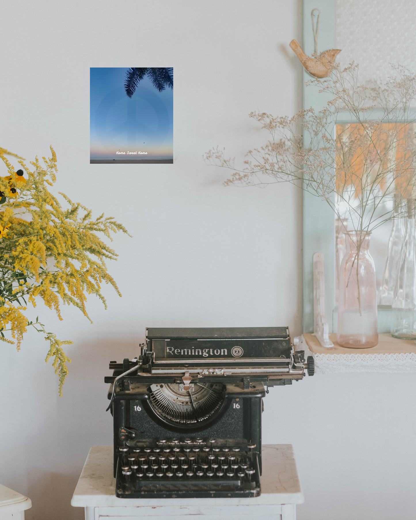 Vintage Remington typewriter on a white surface with decorative elements like flowers and beach sunset canvas in the background