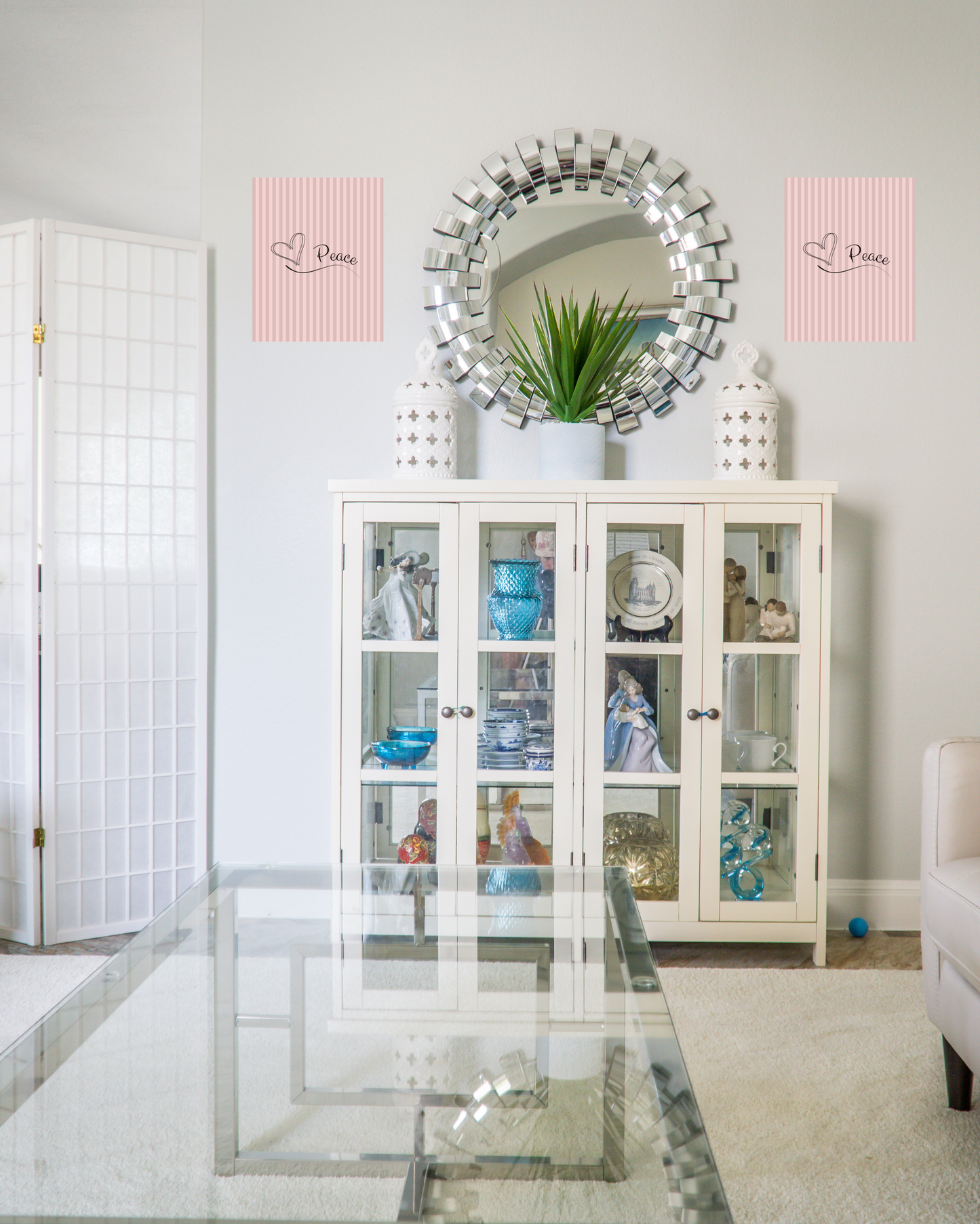 Contemporary living room with a white hue and updated decor including classic pink striped wall art with simple peace design