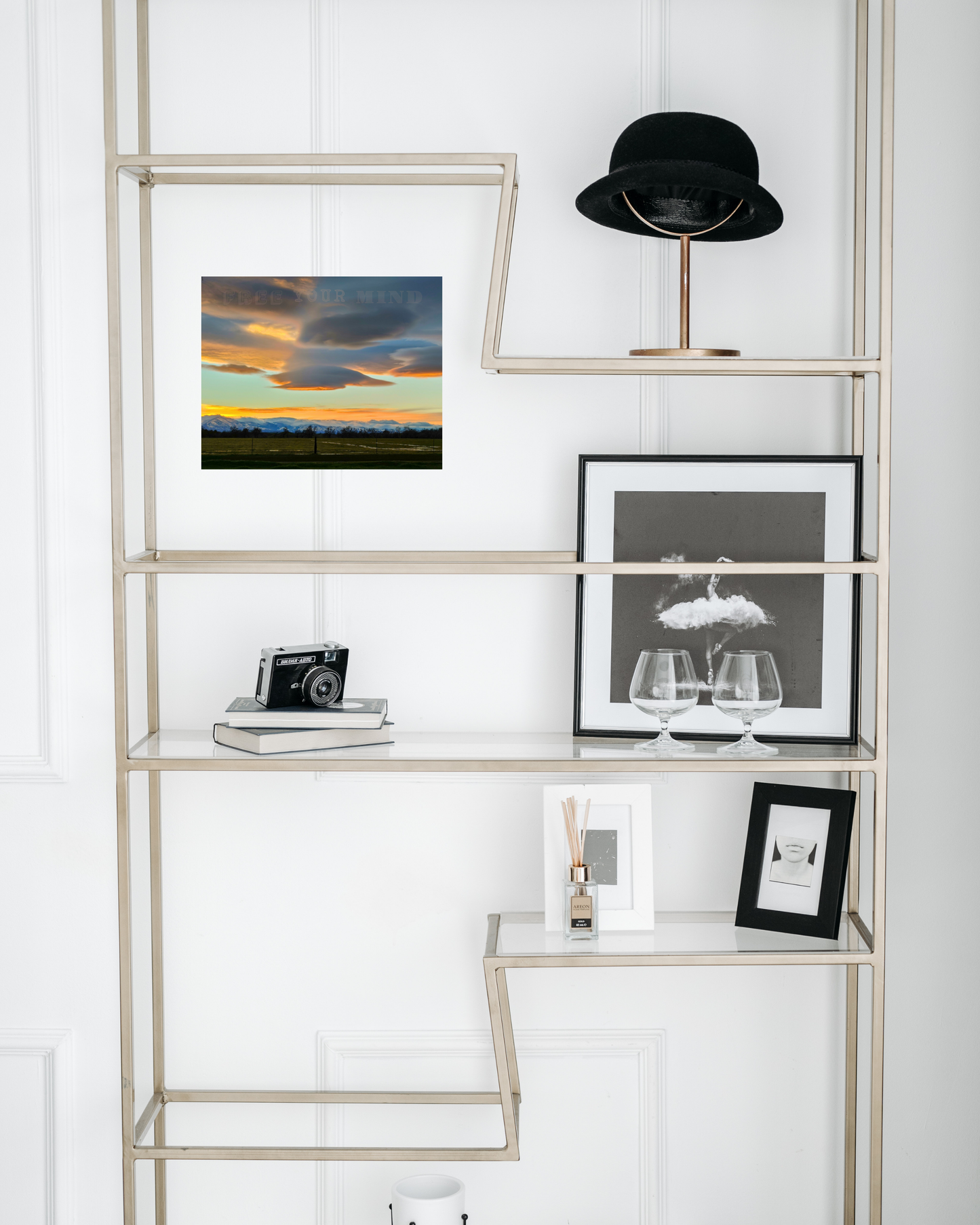 glass bookshelf with artist decor touches and vibrant mountain snowscape hills at dusk with vivid sunset scene