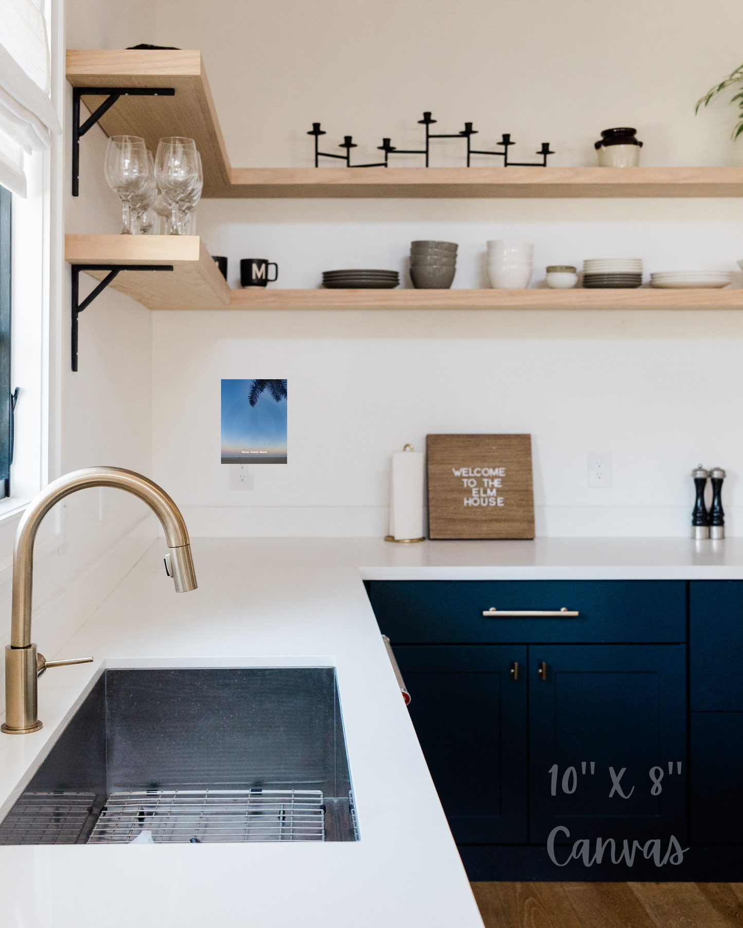 Modern kitchen with white countertops, blue cabinets, and open shelves, offset by vivid blue beach sunset art