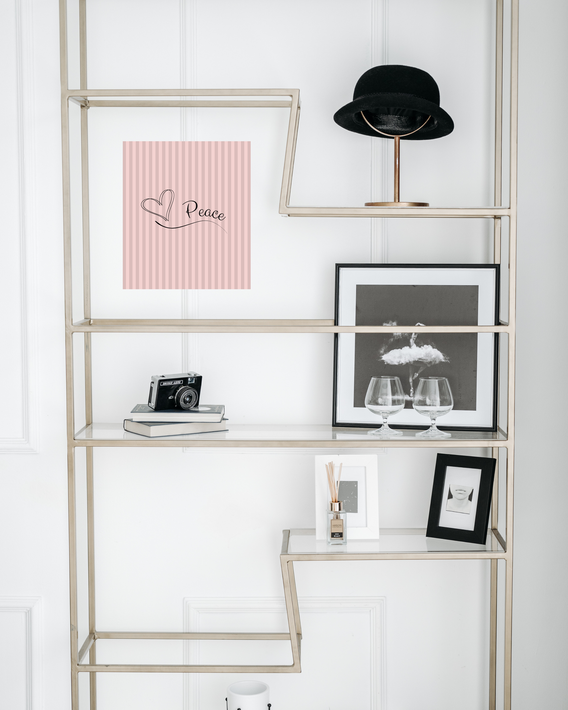 Hollywood style bookshelf showcasing chic pink gray striped print art with simple peace message