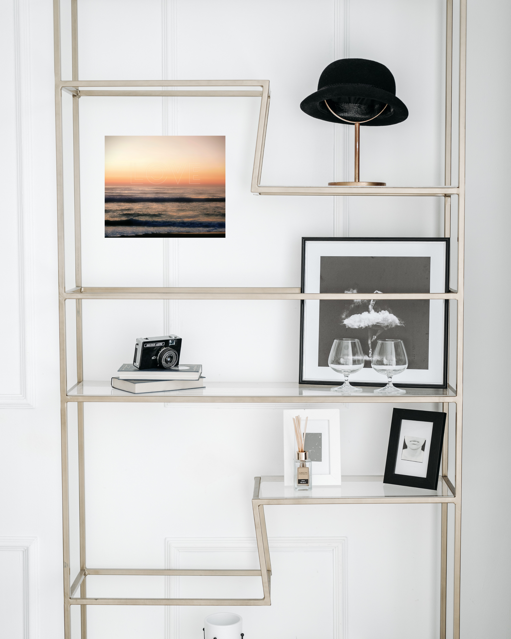 glass bookshelf with chic black and white decor juxtaposed by california ocean wall print with dreamy skies